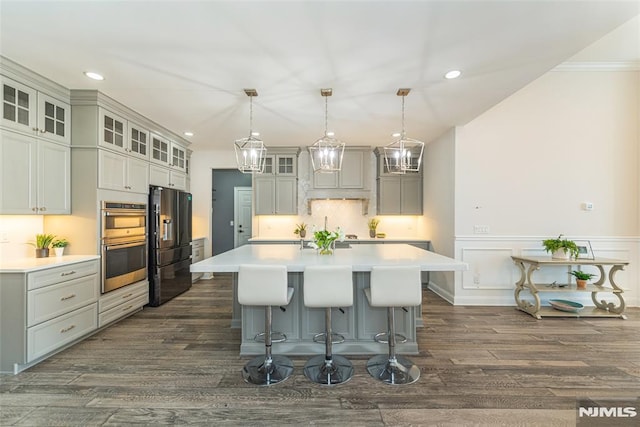 kitchen with a large island, pendant lighting, double oven, ornamental molding, and black refrigerator with ice dispenser