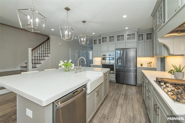 kitchen with sink, gray cabinetry, appliances with stainless steel finishes, an island with sink, and pendant lighting