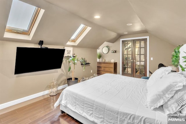 bedroom featuring hardwood / wood-style floors and vaulted ceiling with skylight