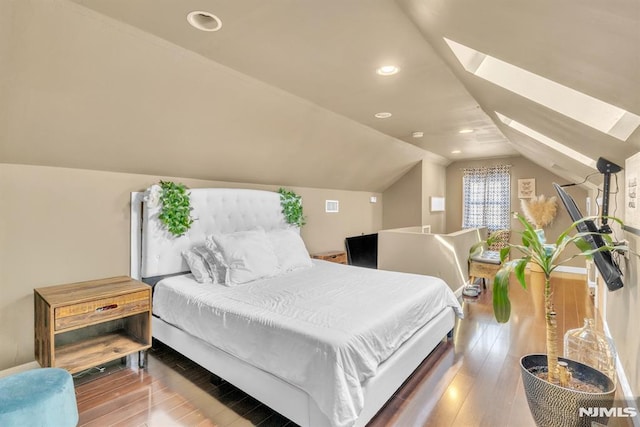 bedroom with wood-type flooring and vaulted ceiling with skylight