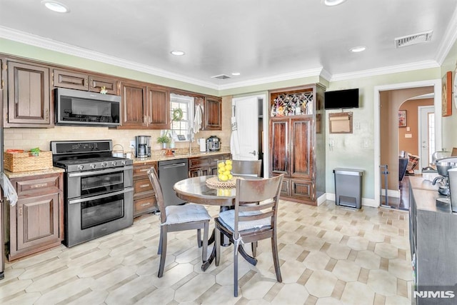 kitchen featuring light stone countertops, ornamental molding, appliances with stainless steel finishes, and tasteful backsplash