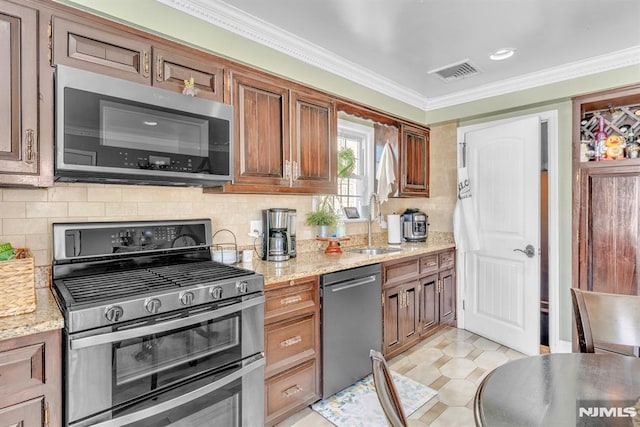 kitchen featuring light stone counters, sink, backsplash, and stainless steel appliances