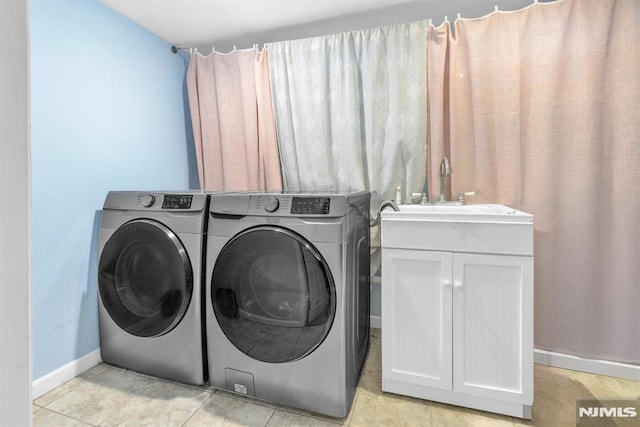 washroom with washing machine and dryer, light tile patterned floors, cabinets, and sink