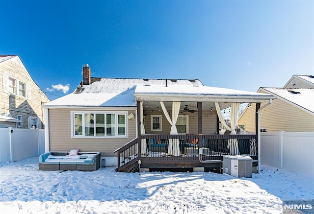 snow covered rear of property with ceiling fan, a deck, and central AC unit