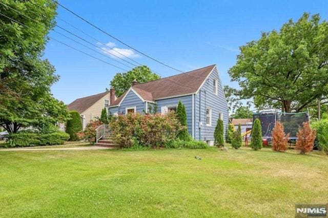 bungalow-style home featuring a front lawn and a trampoline