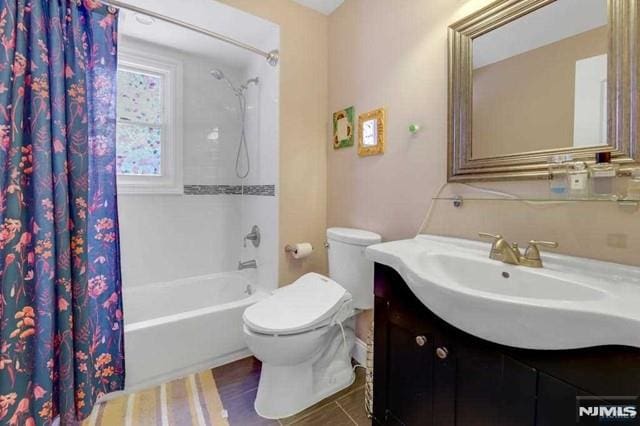 full bathroom featuring toilet, vanity, and shower / bathtub combination with curtain