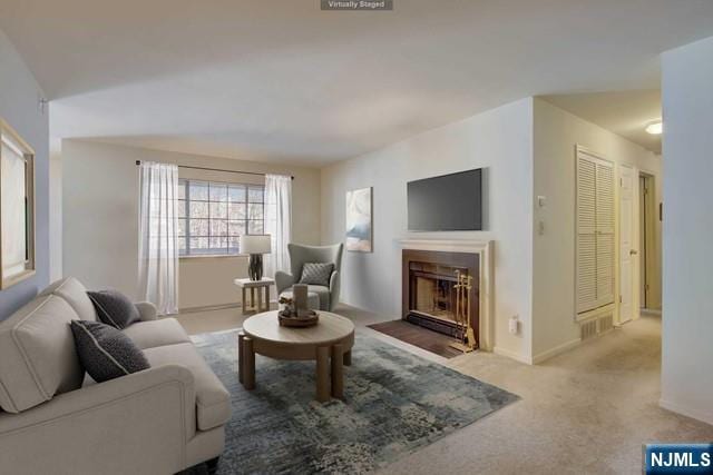 living room featuring baseboards, a fireplace with flush hearth, and light colored carpet