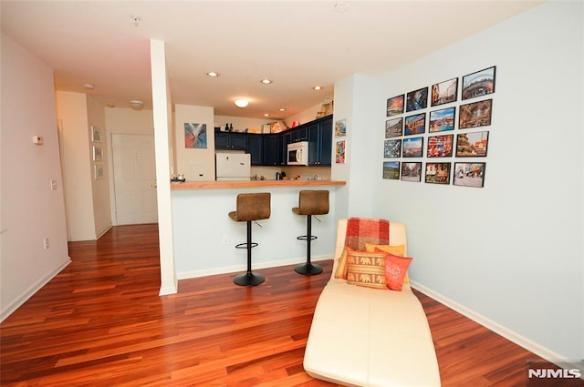 kitchen with hardwood / wood-style floors, a kitchen breakfast bar, blue cabinetry, refrigerator, and kitchen peninsula