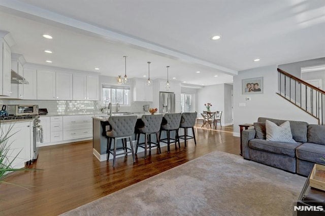 kitchen featuring hanging light fixtures, white cabinets, stainless steel fridge with ice dispenser, dark hardwood / wood-style floors, and a kitchen island