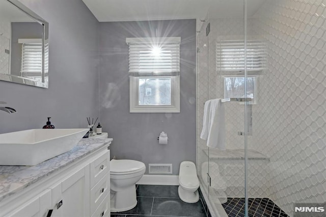 bathroom with a shower with door, toilet, vanity, and tile patterned flooring