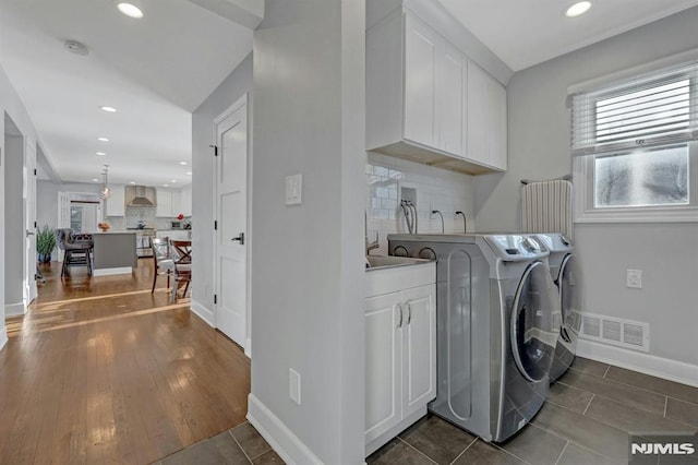 laundry area featuring washing machine and dryer, dark tile patterned flooring, and cabinets