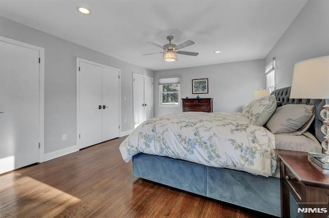 bedroom featuring ceiling fan, two closets, and dark hardwood / wood-style flooring