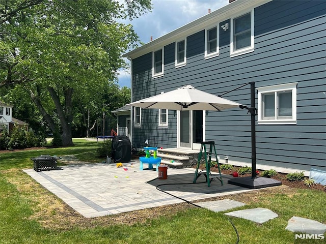 back of property featuring an outdoor fire pit, a yard, and a patio area