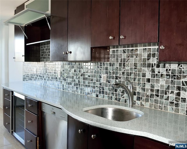 kitchen featuring wine cooler, sink, stainless steel dishwasher, light stone countertops, and backsplash