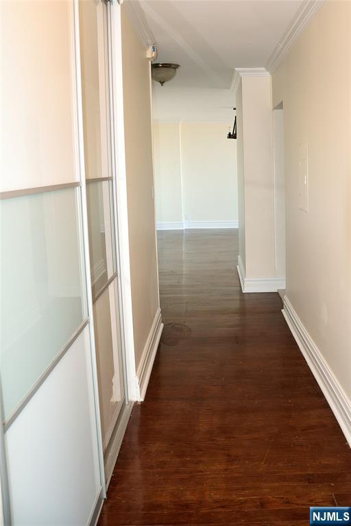 hallway featuring ornamental molding and dark hardwood / wood-style floors