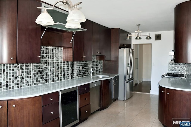 kitchen with hanging light fixtures, sink, stainless steel appliances, and beverage cooler