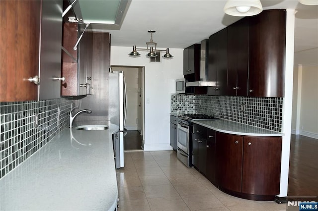 kitchen featuring sink, light tile patterned floors, stainless steel appliances, tasteful backsplash, and wall chimney exhaust hood