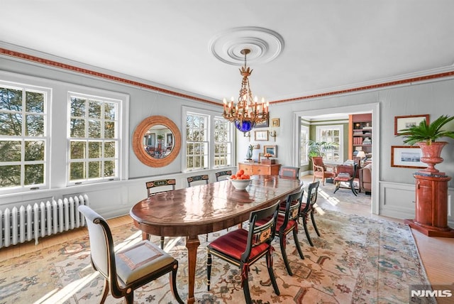 dining space with light hardwood / wood-style flooring, radiator, a notable chandelier, and ornamental molding