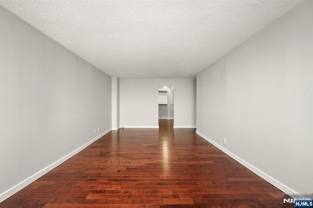 empty room featuring dark hardwood / wood-style flooring and a textured ceiling