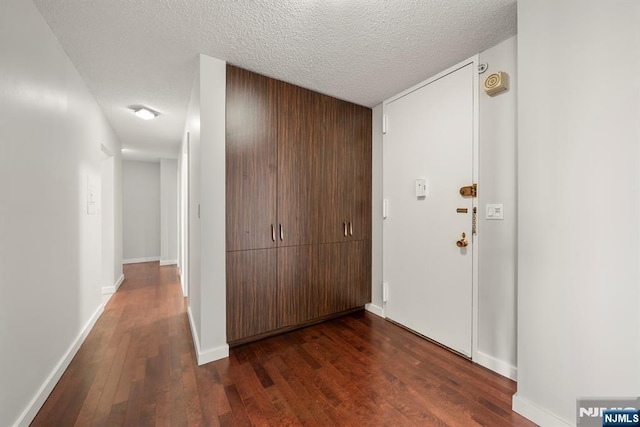 hallway featuring dark hardwood / wood-style flooring and a textured ceiling