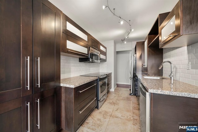 kitchen with sink, backsplash, dark brown cabinetry, stainless steel appliances, and light stone countertops