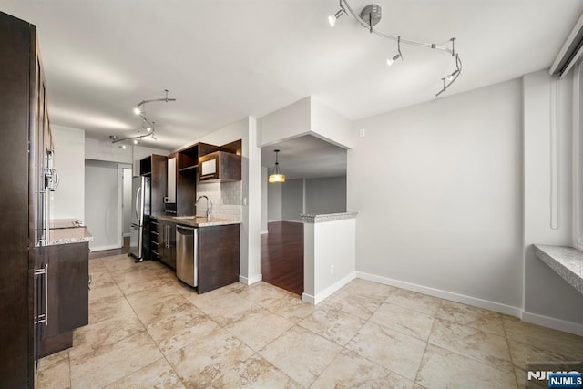 kitchen featuring appliances with stainless steel finishes, sink, backsplash, light stone countertops, and dark brown cabinets