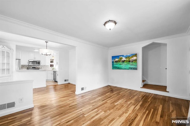 unfurnished living room featuring ornamental molding and light wood-type flooring