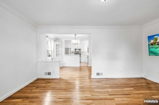 unfurnished living room with light wood-type flooring, crown molding, and a notable chandelier