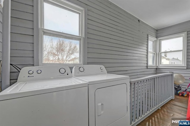 clothes washing area featuring independent washer and dryer and wood walls