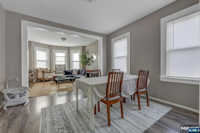 dining space featuring hardwood / wood-style flooring, a healthy amount of sunlight, and cooling unit