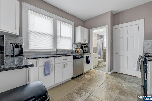 kitchen with sink, stainless steel appliances, white cabinets, light tile patterned flooring, and dark stone counters