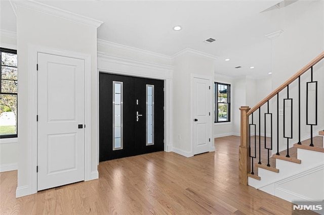 foyer entrance featuring crown molding and light wood-type flooring