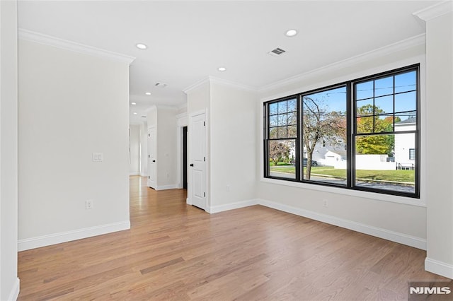 empty room with light hardwood / wood-style floors, a wealth of natural light, and ornamental molding