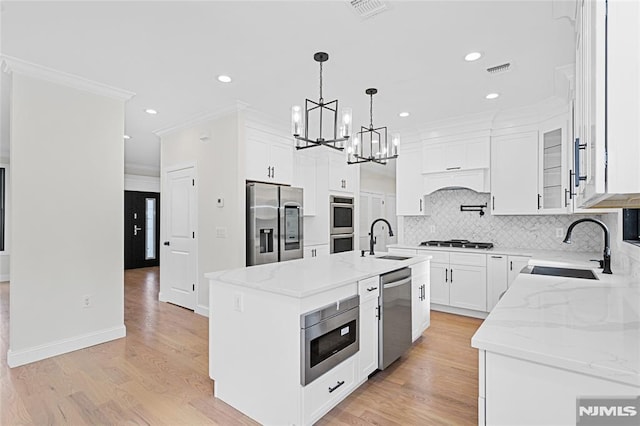 kitchen with a center island, white cabinets, sink, pendant lighting, and stainless steel appliances