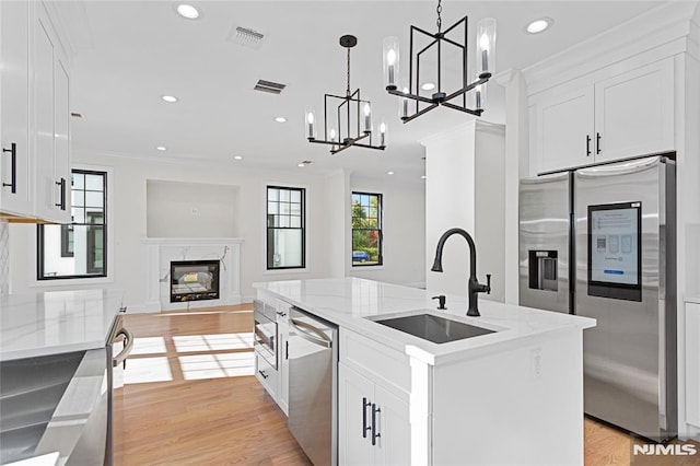 kitchen with sink, an island with sink, white cabinetry, and appliances with stainless steel finishes