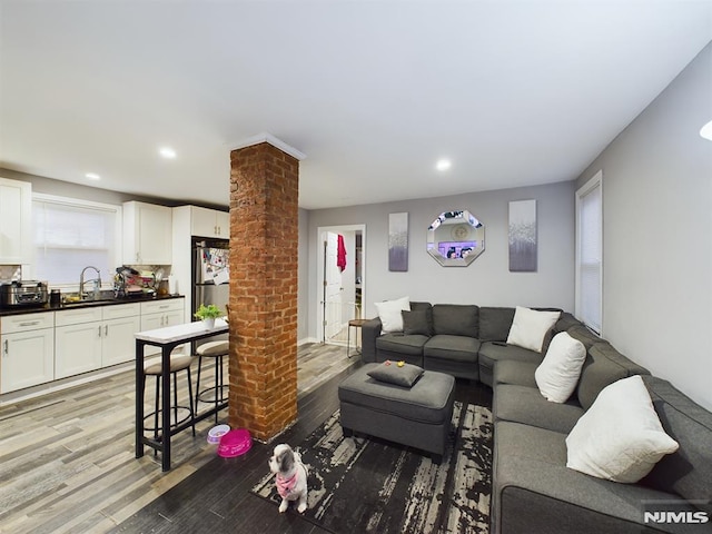 living room featuring sink, decorative columns, and light hardwood / wood-style flooring