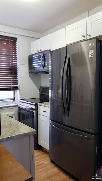 kitchen featuring white cabinets, light hardwood / wood-style flooring, and stainless steel appliances