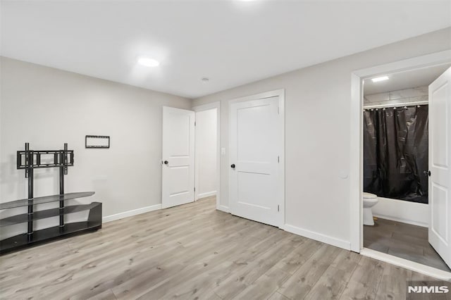 unfurnished bedroom with a closet, light hardwood / wood-style floors, and ensuite bath