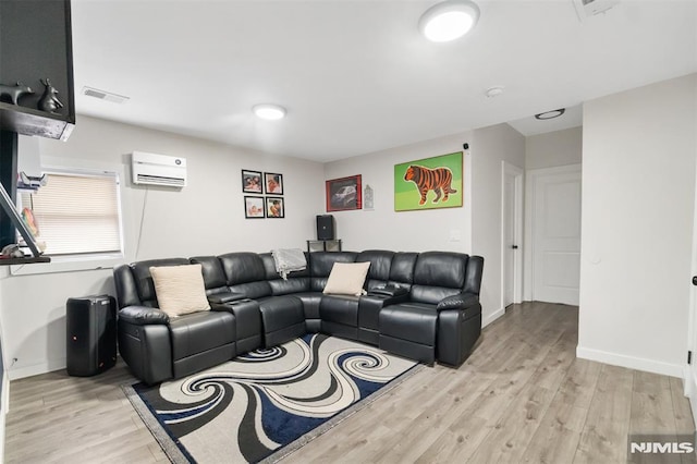 living room with a wall mounted air conditioner and light hardwood / wood-style flooring