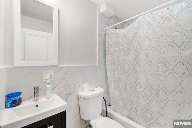 full bathroom featuring toilet, shower / bath combination with curtain, vanity, and tile walls