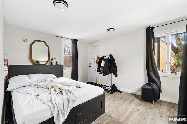 bedroom with multiple windows and light wood-type flooring