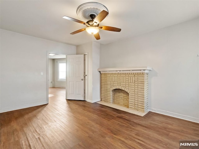 unfurnished living room with hardwood / wood-style flooring, ceiling fan, and a fireplace