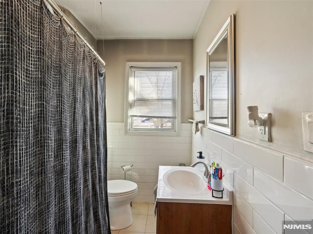 bathroom featuring tile patterned flooring, tile walls, toilet, vanity, and a shower with shower curtain