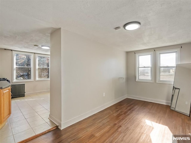 empty room featuring light hardwood / wood-style floors, a textured ceiling, and radiator