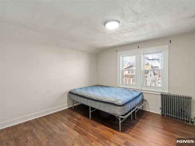 bedroom with a textured ceiling, radiator, lofted ceiling, and dark hardwood / wood-style flooring