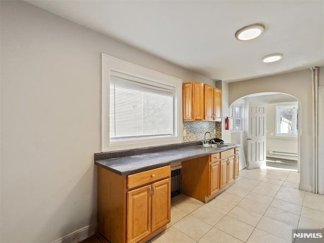 kitchen with sink, backsplash, light tile patterned floors, and a baseboard radiator