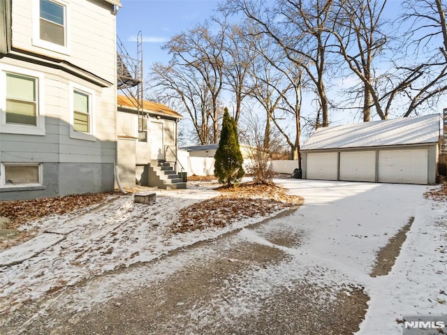 view of snowy exterior with a garage and an outdoor structure