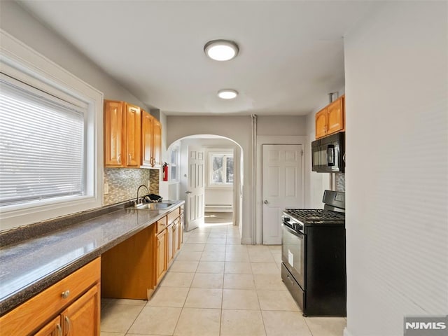 kitchen featuring black appliances, a baseboard heating unit, decorative backsplash, sink, and light tile patterned floors