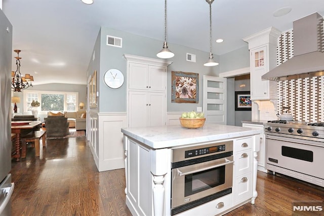 kitchen featuring wall chimney exhaust hood, visible vents, appliances with stainless steel finishes, white cabinets, and glass insert cabinets