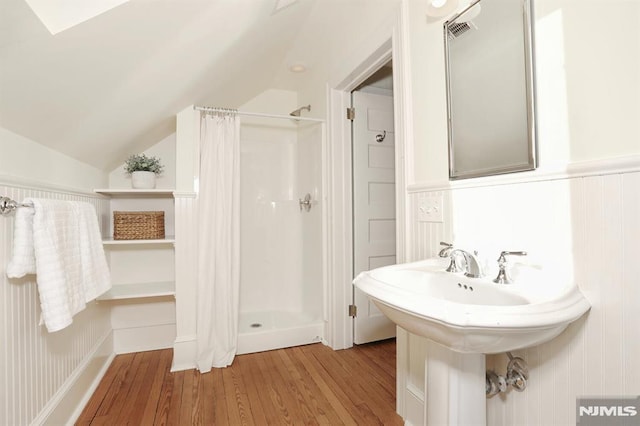 bathroom with wood finished floors, a stall shower, visible vents, a wainscoted wall, and vaulted ceiling